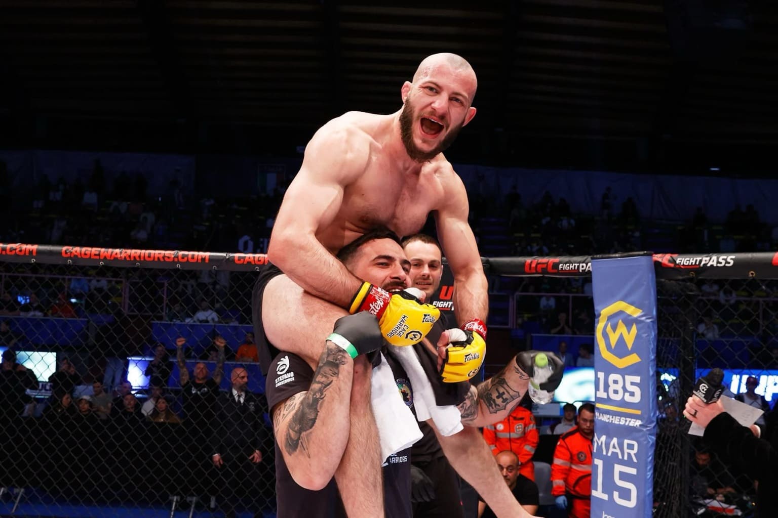 Atleta dell’Elite Fight Academy festeggia la vittoria nella gabbia, sollevato sulla spalle di un compagno di squadra