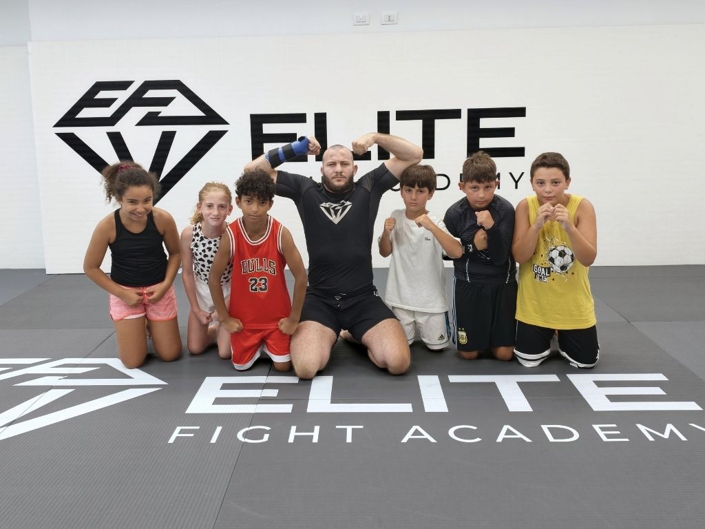 Istruttore e bambini della classe MMA Kids in posa sul tatami