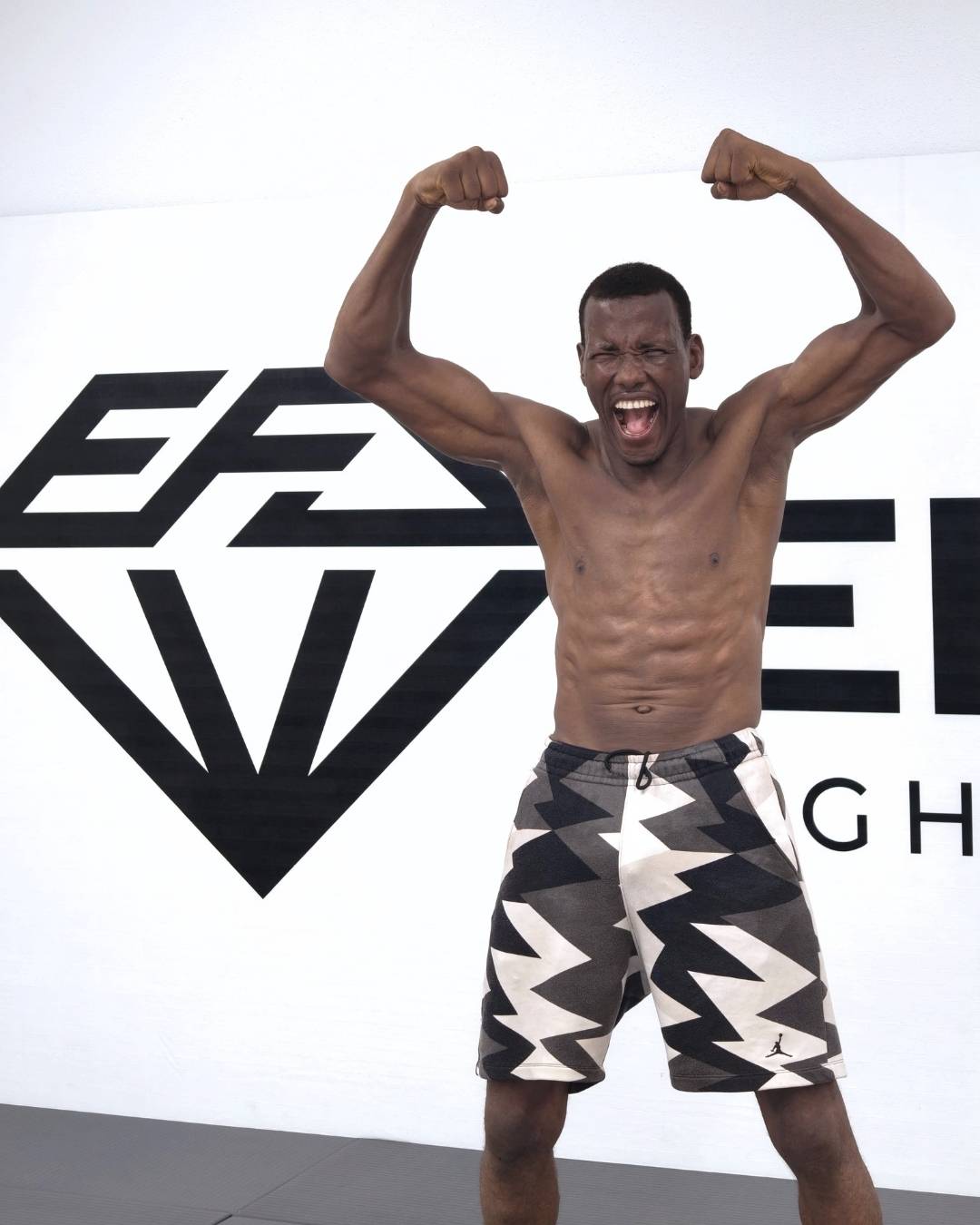 Atleta di MMA che esulta sul tatami davanti alla parete con il logo Elite Fight Academy