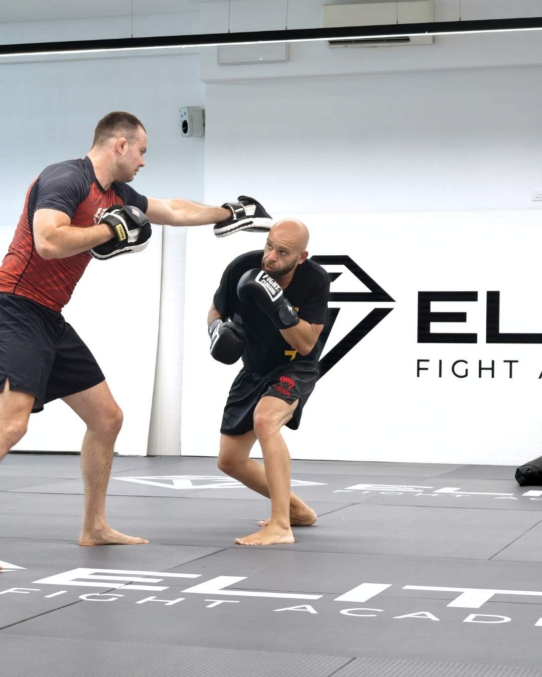 Allenatore tiene i colpitori mentre un atleta di MMA lavora sulle combinazioni